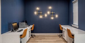 Ein zeitgemäßer Arbeitsbereich mit einer dunkelblauen Wand, einem weißen Schreibtisch und zwei Stühlen.