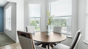 A dining area with a round table, four chairs, and a vase with flowers.