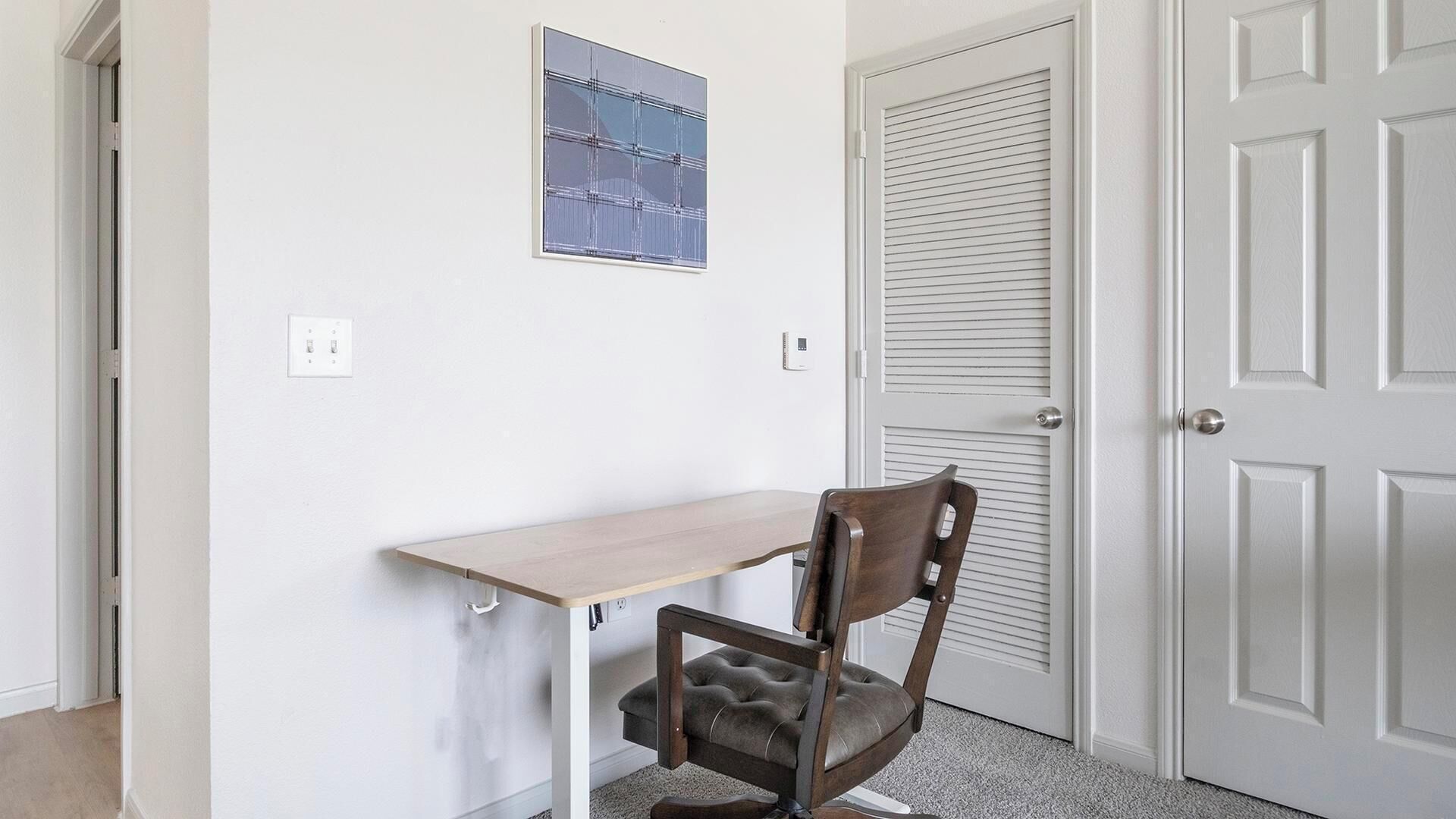 Una habitación con escritorio, silla y puerta de diseño persiana.