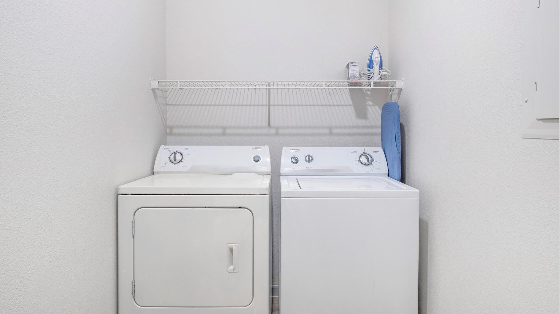 Een wasruimte met twee witte wasmachines en een droogrek.