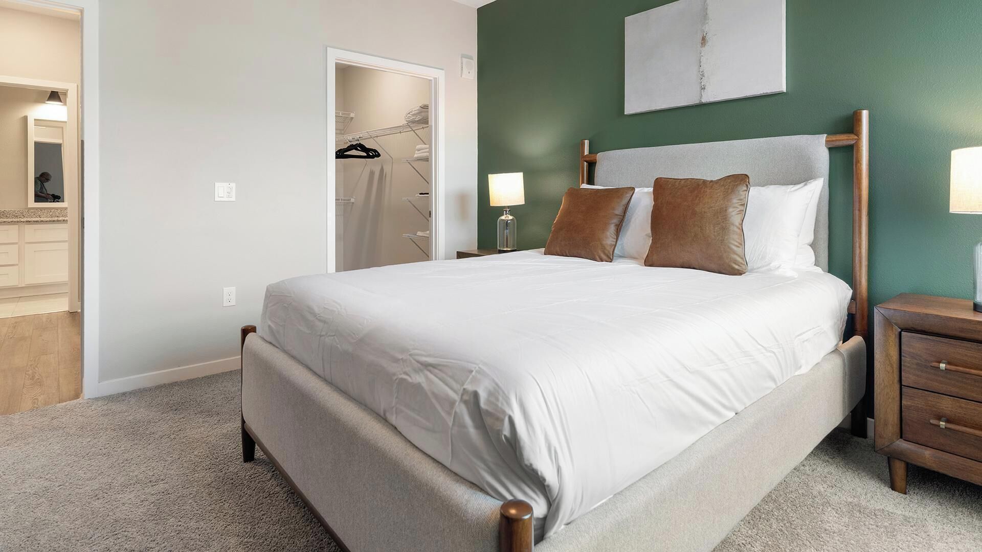 Une chambre à coucher comprenant un lit, des tables de chevet, une commode, une lampe, une armoire et un miroir.