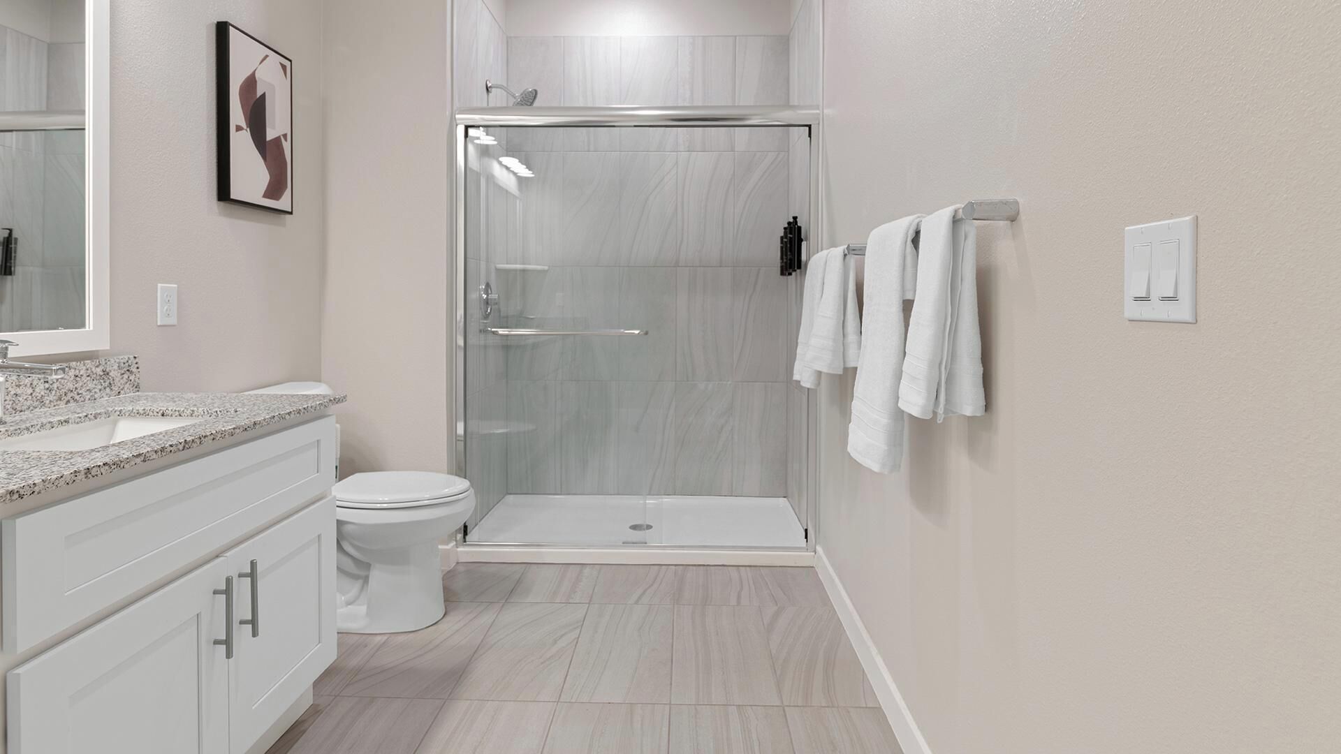 Un baño moderno con cabina de ducha de vidrio, inodoro blanco y encimera de mármol.