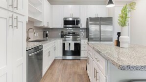 Una cocina moderna con armarios blancos, electrodomésticos de acero inoxidable y encimera de granito.