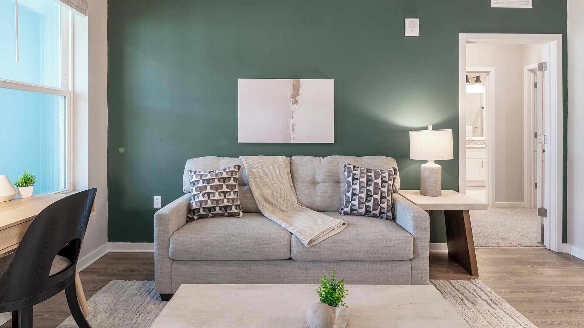 A living room with a sofa, a coffee table, a lamp, and a painting on the wall.