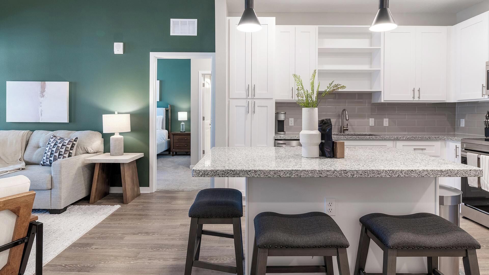 A modern kitchen with white cabinets, a granite countertop, and a central island with stools.