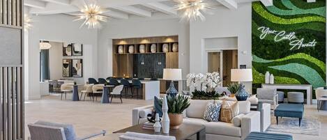 Een ruime woonkamer met een moderne keuken, eethoek en een groene wand met de tekst 'Your Castle Awaits'.