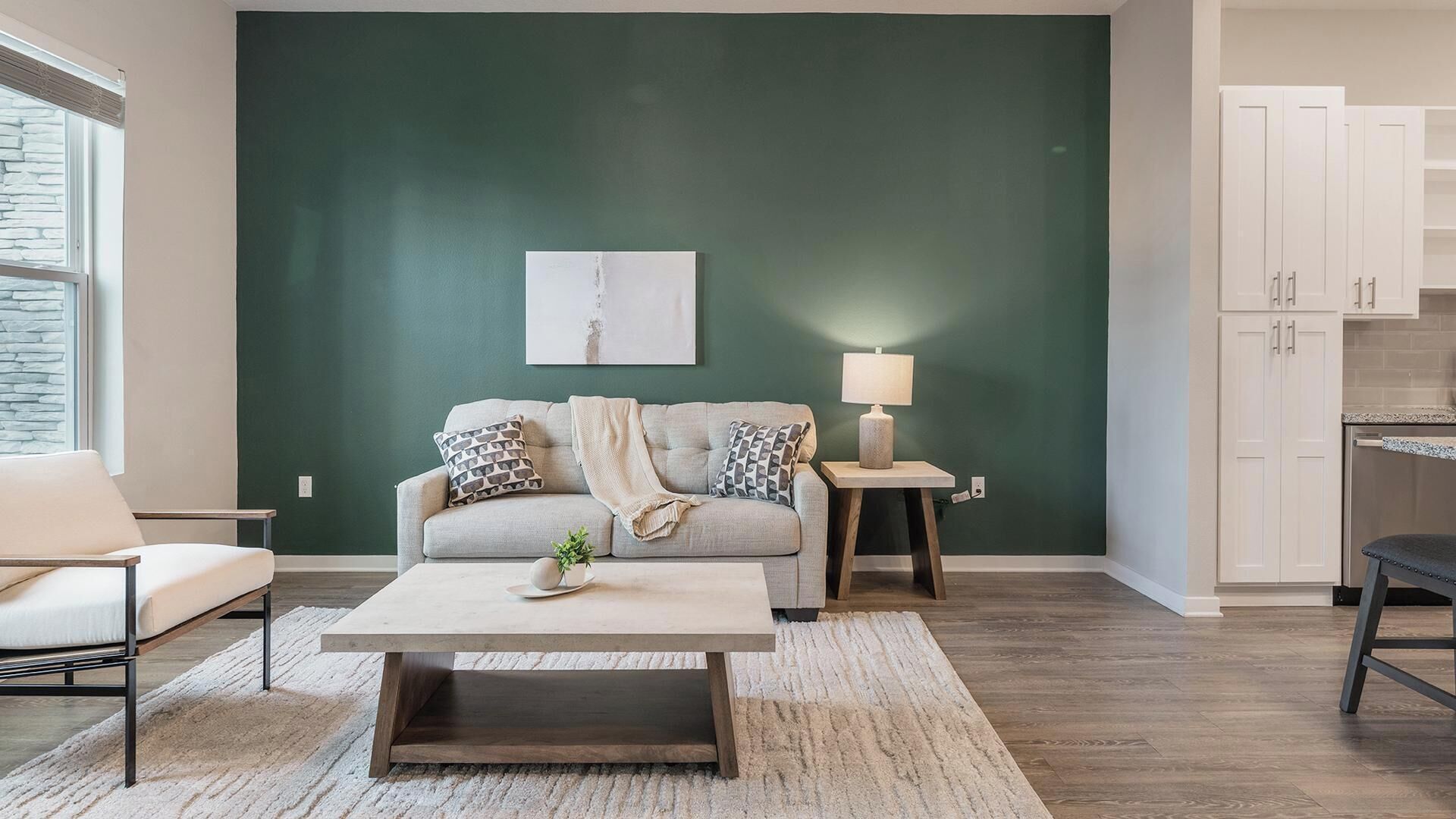 Un salon avec un mur d’accent vert, un canapé, une table basse et une lampe.