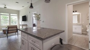 A modern kitchen with granite countertops, a dining area with a chair, and a view of the outdoors. - Landing | Spectacular 1BD, Yoga Studio, Gym (Four Corners)