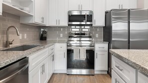 A modern kitchen with stainless steel appliances, white cabinetry, and granite countertops. - Landing | Stunning 1BD, Gym, Yoga Studio (Four Corners)
