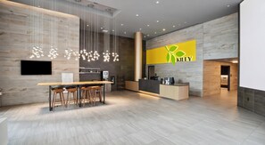 A modern reception area with a wooden reception desk, a bar with stools, and a large logo on the wall. - Landing | Spectacular 1BD, Gym (Washington)