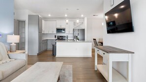 A modern kitchen with white cabinets, stainless steel appliances, and a central island.