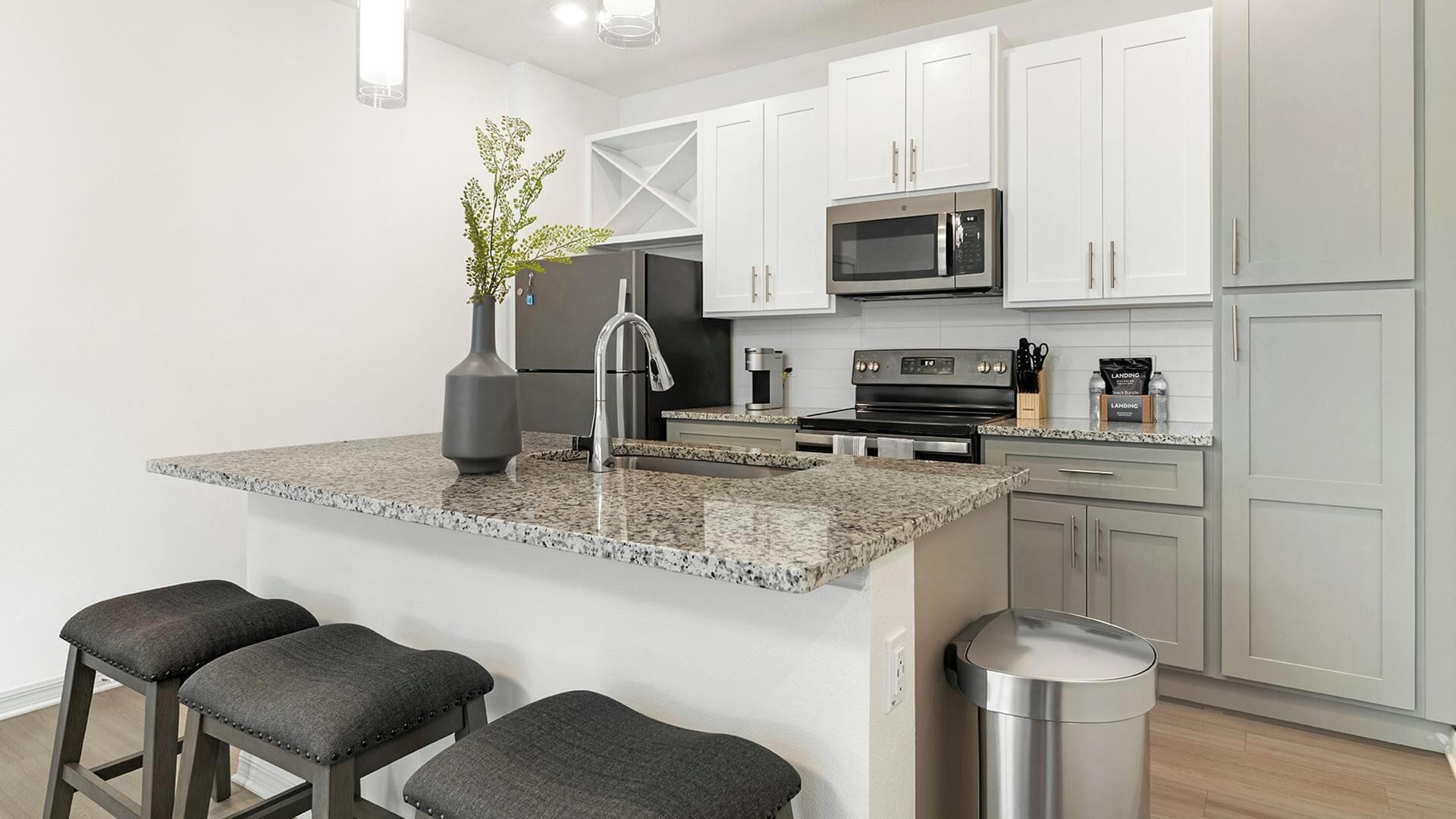 Eine moderne Küche mit Granit Arbeitsplatten, Edelstahlgeräten und einer kleinen Kücheninsel mit Barhocker.