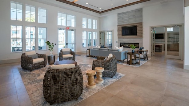 A spacious living area with wicker furniture, a fireplace, and large windows. - Landing | Stunning 1BD, Game Room (Lake Wales)