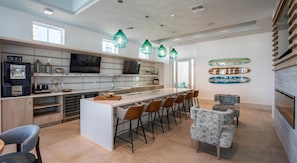 A modern kitchen with a central island, bar stools, and pendant lighting.