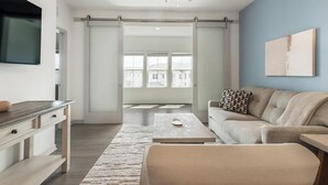 Un soggiorno moderno con divano, tavolino e una porta scorrevole che dà su un balcone.