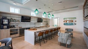 Una cucina moderna con isola centrale, sgabelli da bar e illuminazione a sospensione.