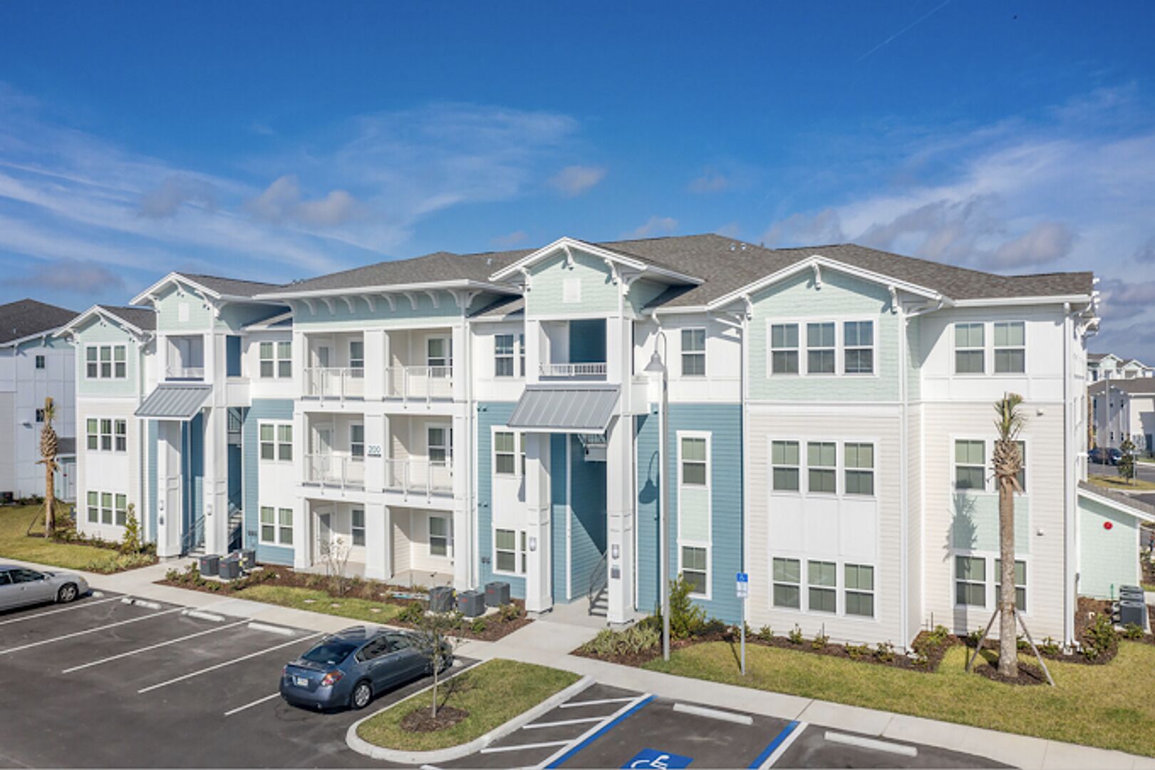 A multi-story residential building with a parking lot in front.