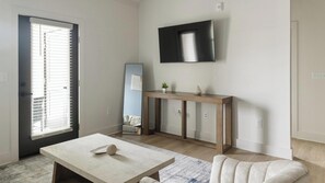 Ein modernes Wohnzimmer mit einem an der Wand befestigten Flachbildfernseher, einem hölzernen Konsolentisch, einem weißen Sofa und einem Marmortisch.