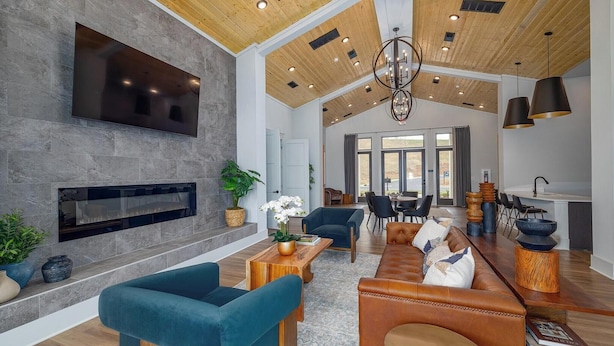 A spacious living area with a fireplace, modern furniture, and a large TV. - Landing | Chic 1BD, Gym, Clubhouse (Asheville)