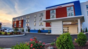 Un hotel moderno con señalización llamativa, varios pisos y un área de estacionamiento.