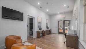 A modern interior with a reception desk, wooden flooring, and a view through a glass door. - Landing | Incredible 1BD, Gym, Clubhouse (Asheville)