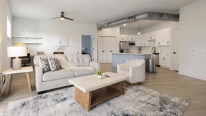 Un salon moderne avec un canapé, une table basse et un tapis. Il y a également un coin cuisine équipé de placards et d’un four à micro-ondes.