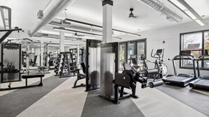 A gym with various exercise equipment, large windows, and a ceiling with ventilation ducts. - Landing | Stunning 2BD, Courtyard, Clubhouse (Dallas)