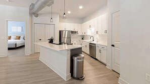 A modern kitchen with white cabinetry, stainless steel appliances, and a central island. - Landing | Spectacular 2BD, Courtyard, Clubhouse (Dallas)