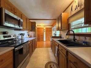 Una cocina con armarios de madera, electrodomésticos de acero inoxidable y un ventanal que proporciona luz natural.