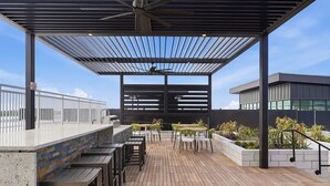 Patio esterno con un bar, posti a sedere e vista sull'edificio.