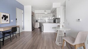 Une cuisine moderne avec des meubles blancs, un réfrigérateur en acier inoxydable et un îlot central doté de sièges.