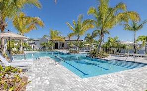 Ein Swimmingpool mit Liegestühlen und Palmen.