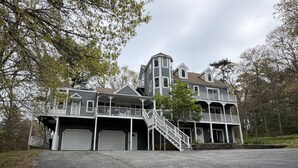 A large, multi-story house with a central staircase, multiple garages, and a porch.