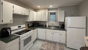 A kitchen with white cabinets, a microwave, a toaster, a coffee maker, and a refrigerator.