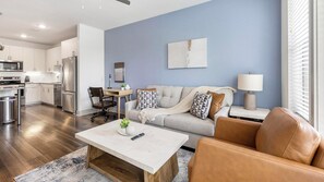 Ein modernes Wohnzimmer mit einer Couch, einem Couchtisch und einem Essbereich mit Tisch und Stühlen.