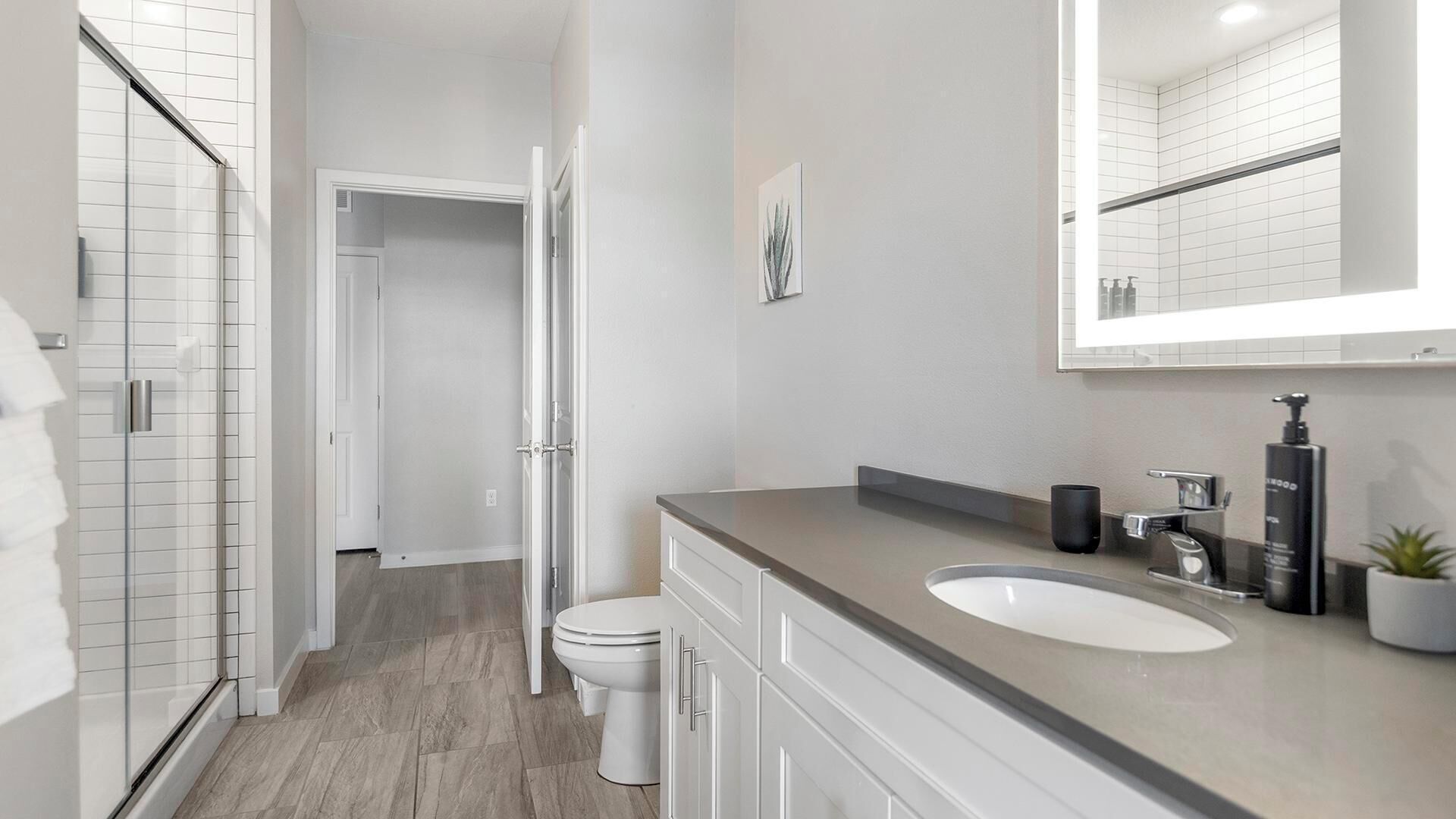 A modern bathroom with a shower, toilet, and sink.