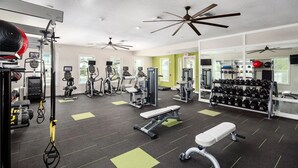 Ein Fitnessraum mit Trainingsgeräten, Bänken und Kurzhanteln.