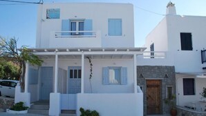 Un immeuble de deux étages avec une façade blanche, des volets bleus et un petit balcon.