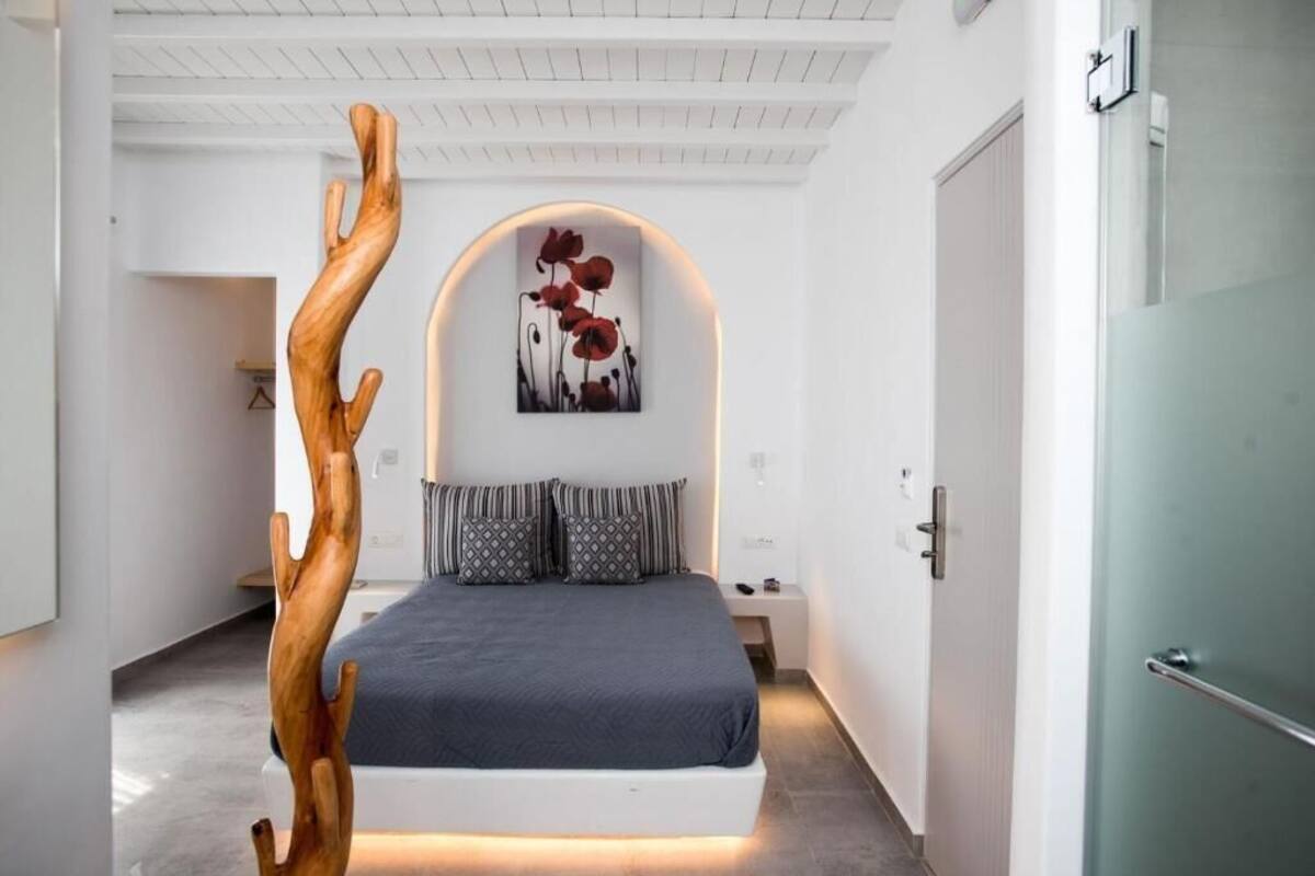 A modern bedroom with a bed, a wooden sculpture, and a wall-mounted artwork.