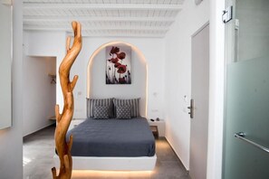 A modern bedroom with a bed, a wooden sculpture, and a wall-mounted artwork. - Mina Cozy Studios (Platis Gialos)
