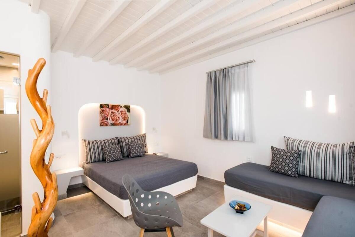 A modern bedroom with a bed, a sofa, a chair, and a small table.