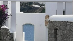 Un bâtiment blanc avec un mur en pierre, une porte bleue et une enseigne avec une flèche.