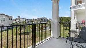 Een balkon met uitzicht op een woonwijk, een stoel en een leuning.