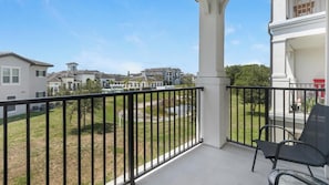 Un balcon donnant sur un quartier résidentiel, avec une chaise et une rambarde.