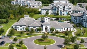 A residential area with modern houses, a roundabout, and a parking lot. - Landing | Spectacular 2BD, Gym (Sun City Center)