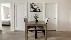 Un comedor con una mesa, sillas, una planta en maceta y una obra de arte colgada en la pared.