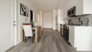 Una cocina moderna con armarios blancos, horno empotrado y microondas.