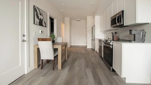 A modern kitchen with white cabinetry, a built-in oven, and a microwave. - Landing | Spectacular 1BD in Columbia Heights (Washington)