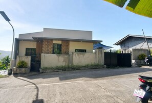 A modern two-story house with a flat roof, a gated entrance, and a parked motorcycle.