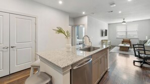 A modern kitchen with granite countertops, stainless steel appliances, and a view into the living area. - Landing | Spectacular 1BD, Gym, Clubhouse (Rockwall)